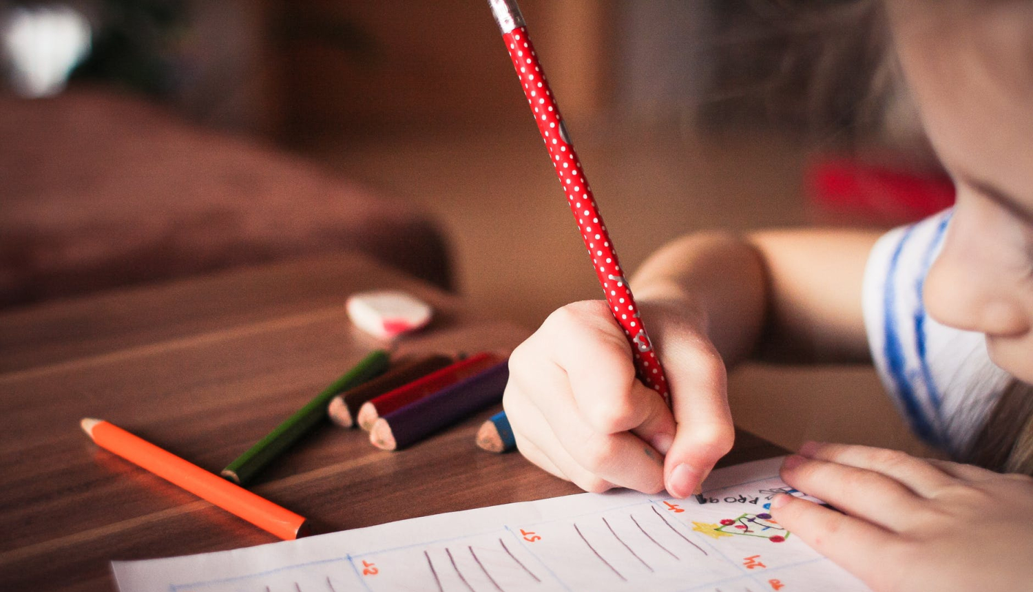 Skolniece raksta burtnīcā ar zīmuli