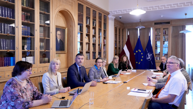 Semināra dalībnieki sēž pie galda Ministru kabineta bibliotēkā