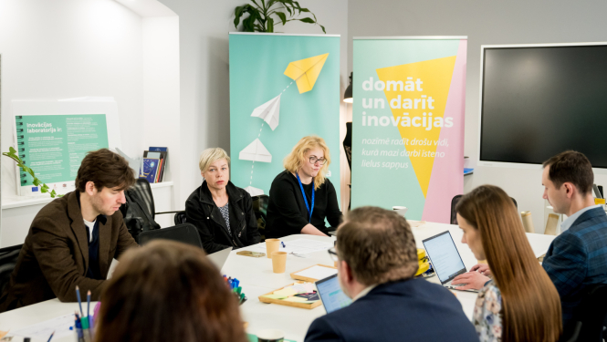 Inovāciju sprints - dalībnieki sēž pie galda, sarunājas