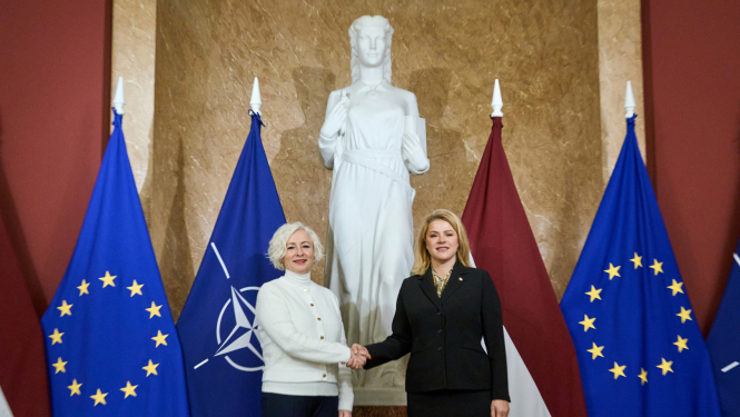 Ministru prezidente Evika Siliņa sarokojas ar Saeimas priekšsēdētāju Daigu Mieriņu pie Latvijas un Eiropas Savienības karogiem Ministru kabineta ēkā