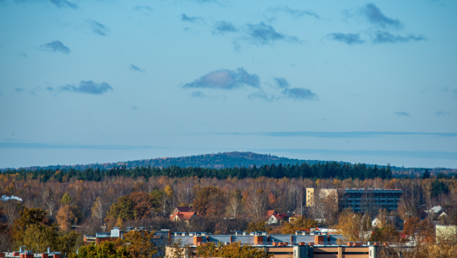 Skats uz pilsētu un tālumā esošu mežu un pakalnu