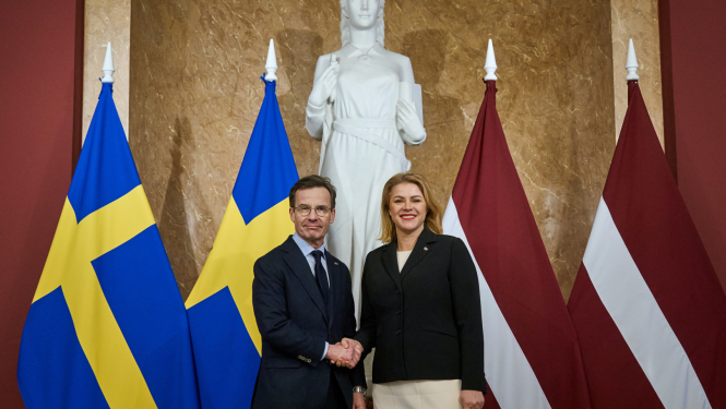 Ministru prezidente Evika Siliņa sarokojas ar Zviedrijas premjerministru Ulfu Kristersonu pie abu valstu karogiem Ministru kabinetā