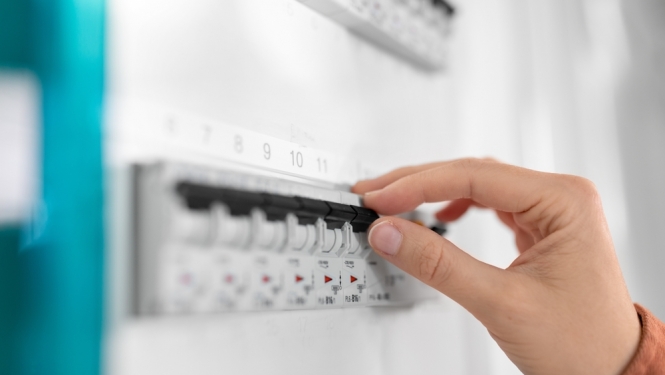 Cilvēka roka tuvplānā slēdz elektrības slēdzi