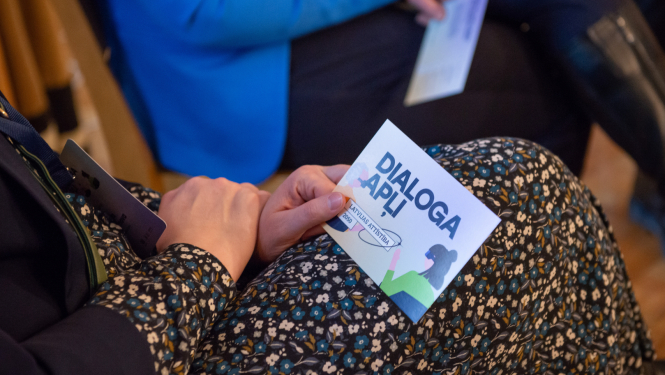Sieviete rokā tur kartīti ar uzrakstu Dialoga apļi