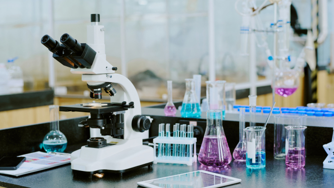 Mikroskops un mēģenes uz galda laboratorijā