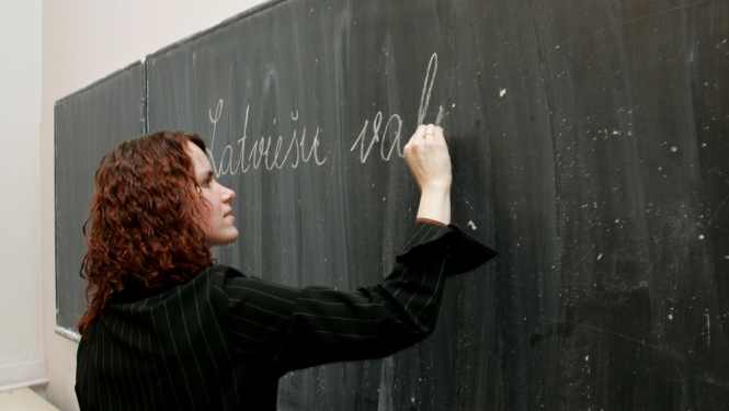 Sieviete raksta uz tāfeles latviešu valodā