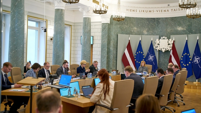 Ministri un Ministru prezidente sēž ap galdu MK sēžu zālē. Notiek MK sēde. 