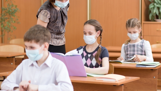 Skolēni un skolotāja klasē ar sejas maskām