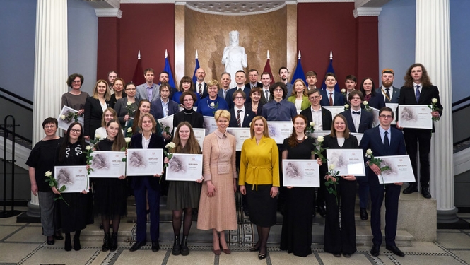 Kopibilde: centrā Izglītības un zinātnes ministre Anda Čakša un Ministru prezidente Evika Siliņa, apkārt Starptautisko olimpiāžu uzvarētāji, viņu pedagogi, konkursa EuroSkills uzvarētājs un prasmju pilnveidotājs, VISC  un VIAA pārstāvji. 