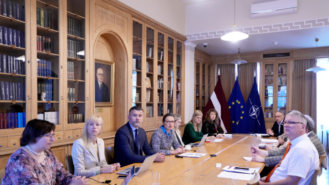 Semināra dalībnieki sēž pie galda Ministru kabineta bibliotēkā