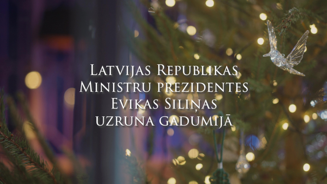 Uzraksts Latvijas Republikas Ministru prezidentes Evikas Siliņas uzruna gadumijā, fonā attēls ar gaismiņām eglītes zaros