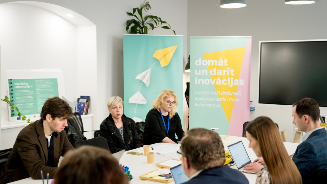 Inovāciju sprints - dalībnieki sēž pie galda, sarunājas