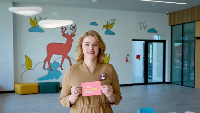 Ministru prezidente Evika Siliņa tur rokās kartīti ar uzrakstu "Tu esi vislabākā mamma!"