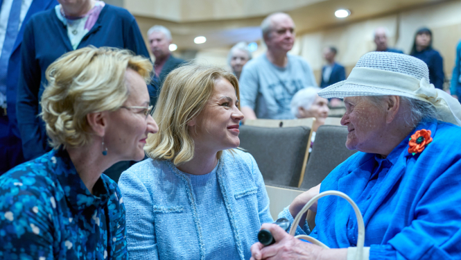 Ministru prezidente Evika Siliņa sarunā ar Latvijas simtgadnieku salidojuma dalībnieci, Ministru prezidentei kreisajā pusē Izglītības un zinātnes ministre Dace Melbārde