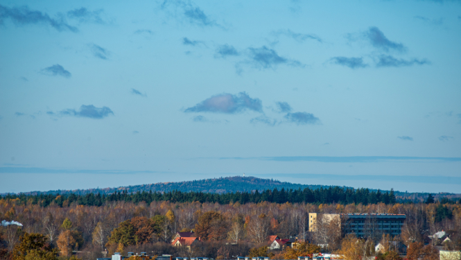 Skats uz pilsētu un tālumā esošu mežu un pakalnu