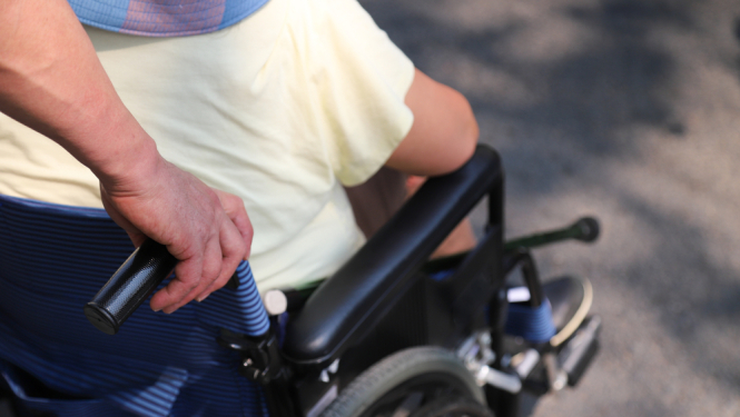 Asistents stumj cilvēku ratiņkrēslā