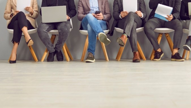 Cilvēki sēž rindā. Dažiem rokās dators, dažiem dokumenti. 