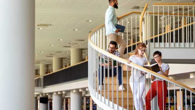 Studenti augstskolā. Fonā grāmatu plaukti. 