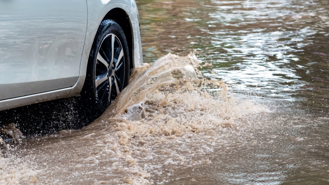 Automašīna brauc cauri dziļai peļķei