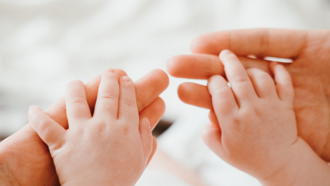 Mazulis ar abām rokām pieķēries vecāka rokām