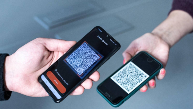 Attēls: divi telefoni, notiek Covid-19 sertifikāta skenēšana