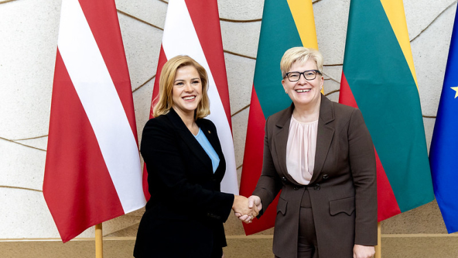 Evika Siliņa un Ingrīda Šimonīte sasveicinās. Fonā Latvijas un Lietuvas karogi. 
