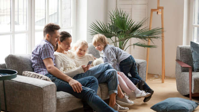 Ģimene jaunā mājoklī uz dīvāna. Mamma, tētis un 2 bērni. 