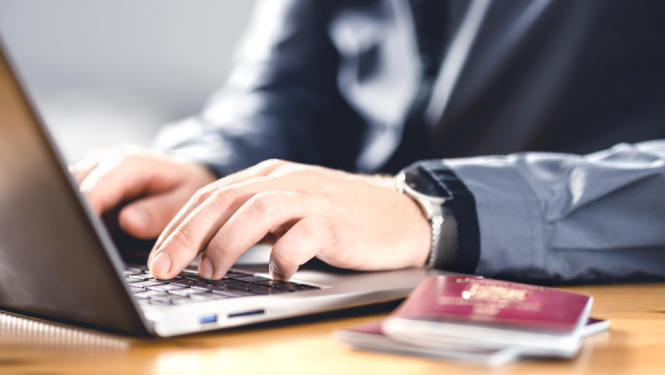 Vīrietis raksta uz datora, uz galda pase. 