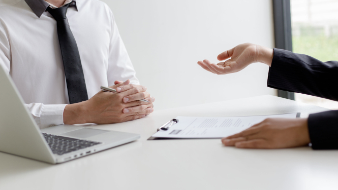 Cilvēki sarunājas pie datora katrs savā galda pusē