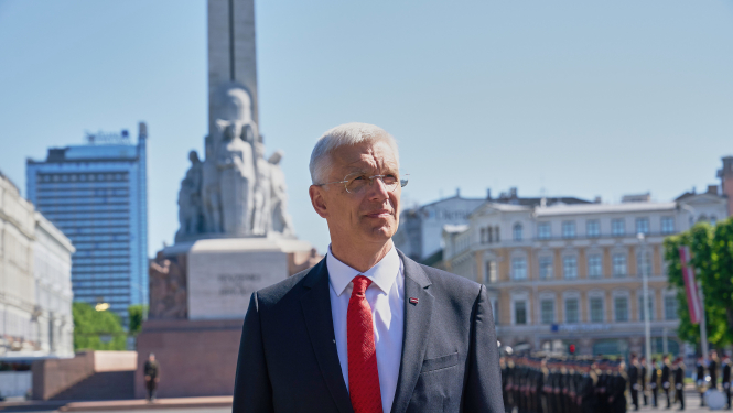 Ministru prezidents Krišjānis Kariņš uzvalkā un sarkanā šlipsē ar Brīvības pieminekli fonā