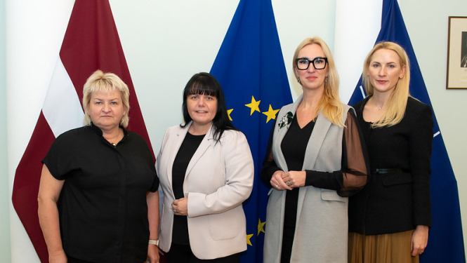 Tikšanās dalībnieces uz Latvijas, Eiropas Savienības un NATO karogu fona