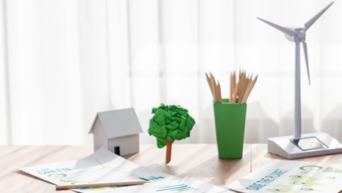 Uz galda dažādi priekšmeti, kas simbolizē zaļo enerģiju, piem, zaļs koks, vēja ģenerators 