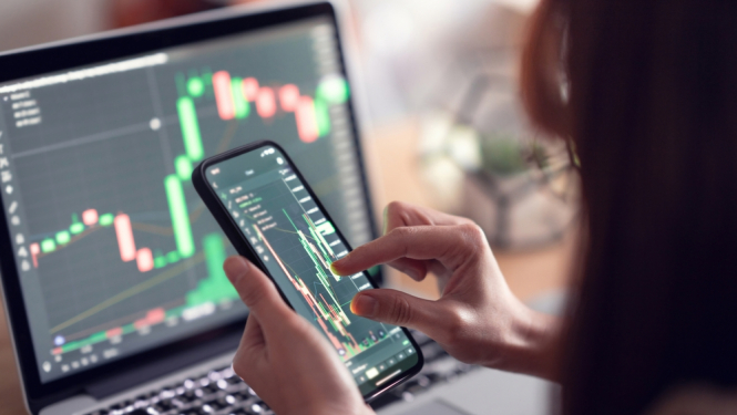 Sieviete telefonā skatās kriptovalūtu biržā. 