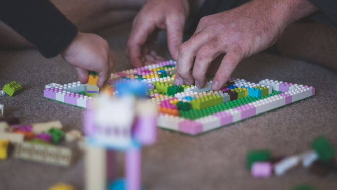 Tētis un bērns spēlē Lego spēli