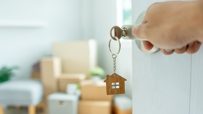 Atslēgu piekariņš mājas formātā. Fonā jauns mājoklis