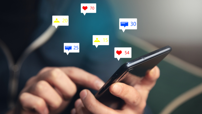 Vīrietis tur rokās telefonu. Sociālo tīklu ikonas.