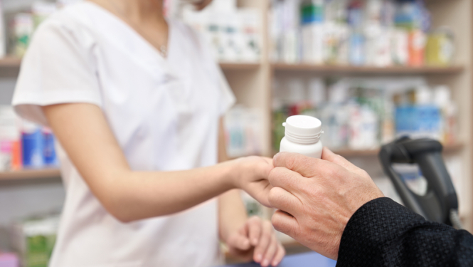 Aptiekā farmaceite pasniedz cilvēkam  medikamentus