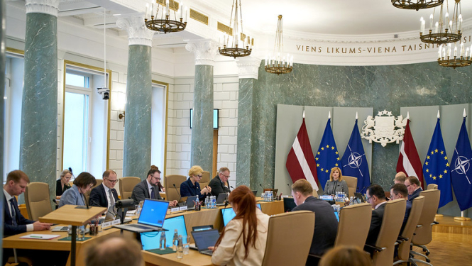 Ministri un Ministru prezidente sēž ap galdu MK sēžu zālē. Notiek MK sēde. 