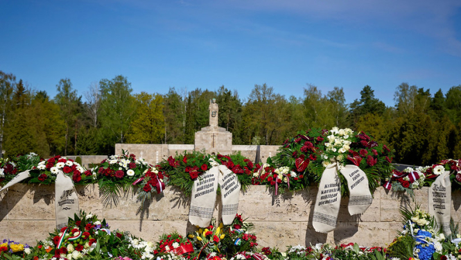 Brāļu kapu siena ar Māti Latviju. Ziedu vainagi ar lentām kritušo karavīru piemiņai. 
