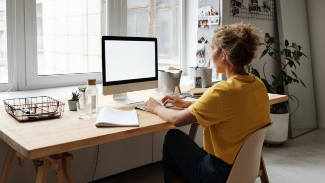 Sieviete pie darba galda un datora