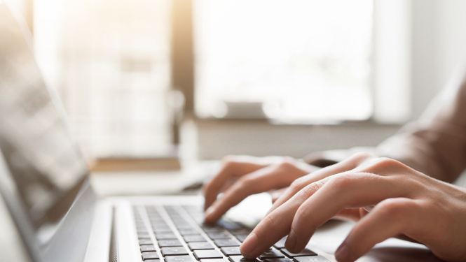 Cilvēka rokas tuvplānā, rakstot uz datora klaviatūras