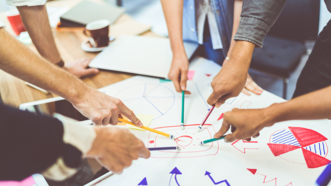 Cilvēki norāda uz zīmējumiem, grafikiem