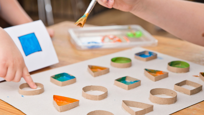 Bērns zīmē ar ūdenskrāsām ģeometriskas figūras