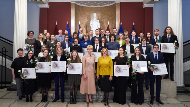 Kopibilde: centrā Izglītības un zinātnes ministre Anda Čakša un Ministru prezidente Evika Siliņa, apkārt Starptautisko olimpiāžu uzvarētāji, viņu pedagogi, konkursa EuroSkills uzvarētājs un prasmju pilnveidotājs, VISC  un VIAA pārstāvji. 