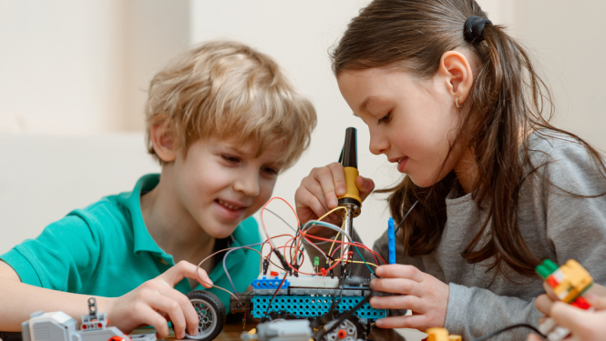 Zēns un meitene darbojas ar tehnoloģijām - būvē auto, kuram pieslēgti vadi