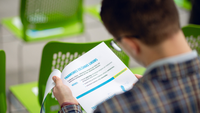 Foto: vīrietis tur rokā lapu, kur rakstīts "Trauksmes cēlēju likums"