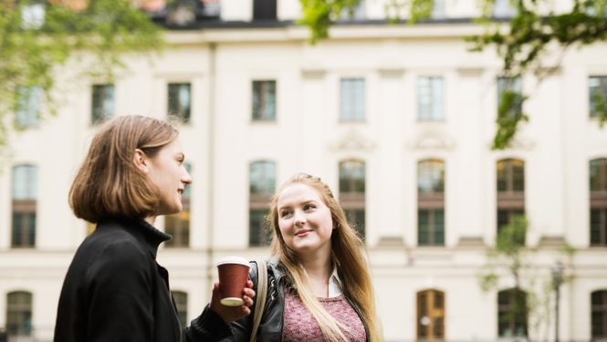 Divas jaunas sievietes, fonā mācību ēka