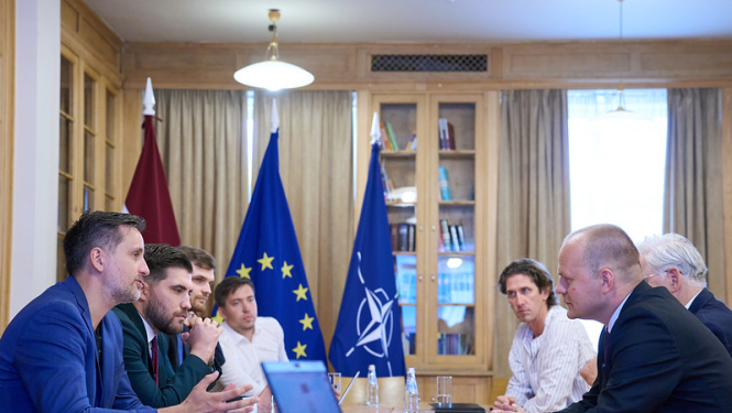 Valdības un Saeimas pārstāvji sēž ar sporta nozares pārstāvjiem pie galda Ministru kabineta bibliotēkā. 