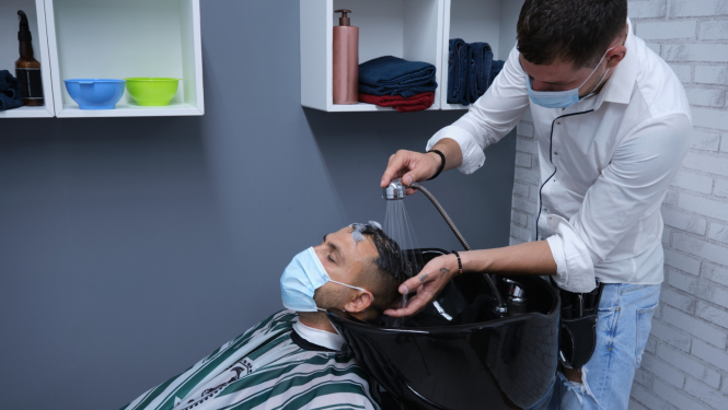 Frizieris frizētavā vīrietim mazgā matus
