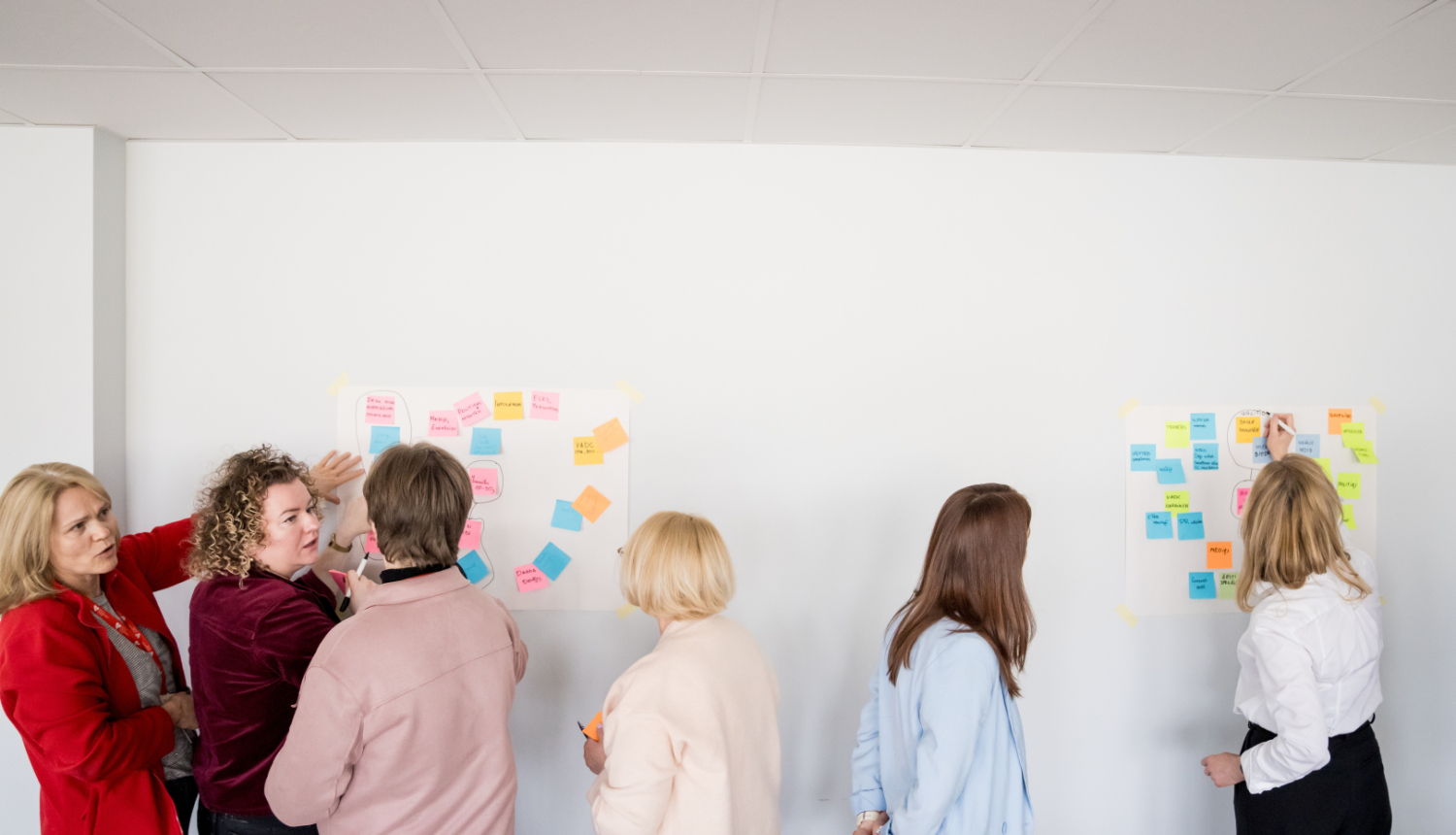 Inovāciju sprints - cilvēki pēta pie sienas piespraustas krāsainas līmlapiņas
